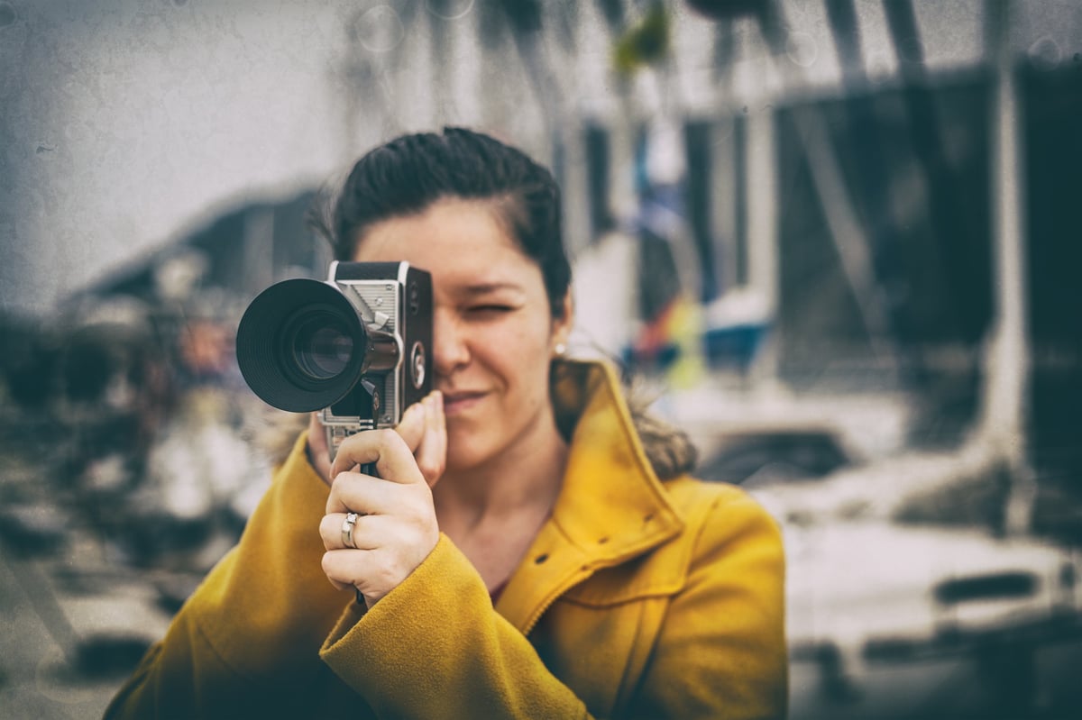 Young filmmaker with vintage camera capturing summer memories
